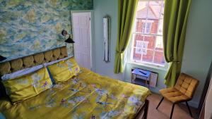 a bedroom with a yellow bed and a window at Philbeach Guest House in Weymouth