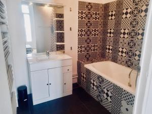 La salle de bains est pourvue d'une baignoire et d'un lavabo. dans l'établissement Spacieux et lumineux appartement vue mer Joliette, à Marseille