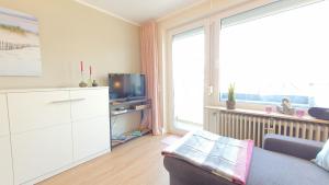 a living room with a couch and a tv and a window at NordseeGlück in Cuxhaven