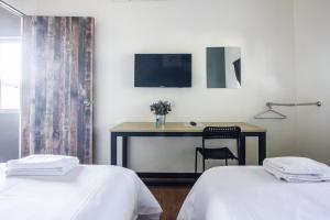 2 Betten in einem Zimmer mit einem Schreibtisch und einem Tisch in der Unterkunft Explore 5BR Gardenhouse Retreats (Free Parking) in Butterworth