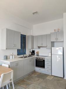a white kitchen with white appliances and a table at Aeraki in Kithnos