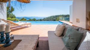 uma sala de estar com um sofá e uma piscina em Villa El Mirador Uno em Es Cubells