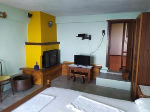 Habitación con cama, TV y mesa. en Triple studio apartment in Mylopotamos Beach, en Tsagkarada