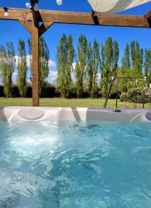 una piscina con pérgola de madera y agua azul en L Amalia au cœur des Châteaux de la Loire et du zoo de Beauval en Sambin