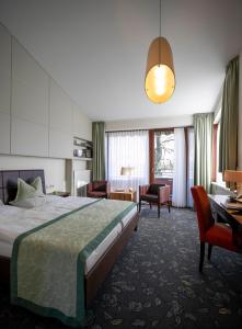 ein Hotelzimmer mit einem Bett, einem Schreibtisch und Stühlen in der Unterkunft Hotel Landhaus Pollmeyer in Friesoythe