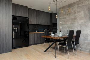 a kitchen with a wooden table and black refrigerator at Apartaments Port Darłówko by Renters in Darłowo