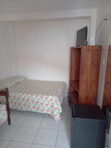 sypialnia z łóżkiem i komodą z telewizorem w obiekcie Pousada Residencial Benfica w mieście Porto Seguro