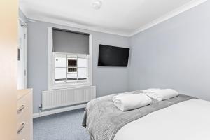 a white bedroom with a bed and a tv at Town House Rooms in Boston