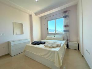 une chambre blanche avec un lit avec une fenêtre dans l'établissement Brand24 Apartment, à Vlorë