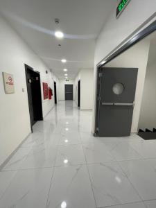 a hallway of a building with a large white tile floor at تربل وان للشقق المخدومة in Ruqaiqah