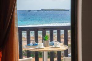 uma mesa com copos e pires numa varanda com vista para o oceano em Hotel Porto Diakofti em Diakofti