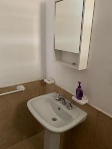 een badkamer met een witte wastafel en een spiegel bij Departamento Puerta del Rio in Villa María