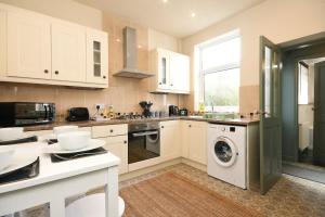 cocina con armarios blancos, lavadora y secadora en Cottage Style 3 bedroom House - Close to City centre & The Peaks en Chesterfield