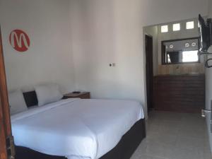 1 dormitorio con 1 cama blanca grande en una habitación en Mugeni Homestay, en Senggigi 