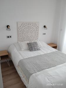 um quarto com uma grande cama branca e duas mesas em Apartamento Isaac junto a la muralla Romana em Lugo