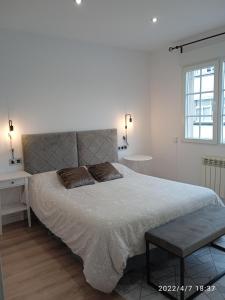 a white bedroom with a large bed and a window at Apartamento Isaac junto a la muralla Romana in Lugo