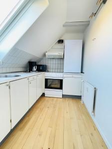 a kitchen with white cabinets and a wooden floor at aday - Reberbansgade Apartment Suite in Aalborg