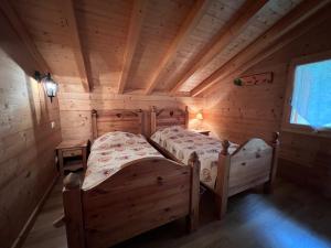 Un dormitorio con dos camas en una cabaña de madera. en L'Aulp De Suz 1 - Demi chalet, en La Clusaz