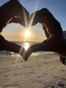 un par de manos formando un corazón con el sol en el fondo en FLAT / APARTAMENTO NA PRAIA DO FORTE, en Cabo Frío