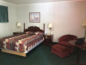 Habitación de hotel con cama y silla en Rapids Inn & Suites, en Wisconsin Rapids