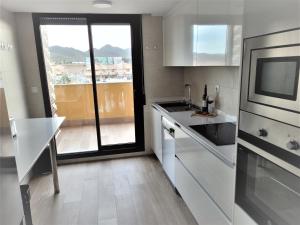 une cuisine avec des placards blancs et une grande fenêtre dans l'établissement Los Flamencos Sea View Apartment, à Carthagène
