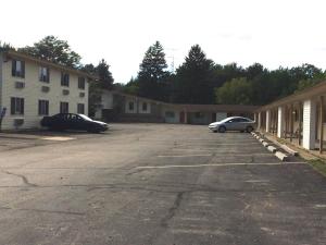un estacionamiento con dos autos estacionados al lado de un edificio en Rapids Inn & Suites, en Wisconsin Rapids