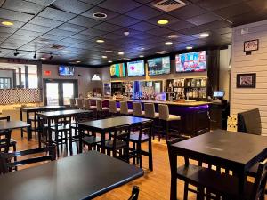 a restaurant with tables and chairs and televisions at Falmouth Inn in Falmouth