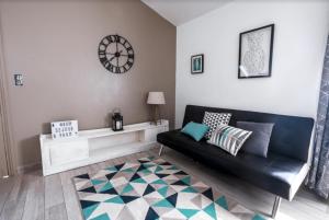 un salon avec un canapé et une horloge au mur dans l'établissement Petite maison de vacance vue mer, au Lavandou