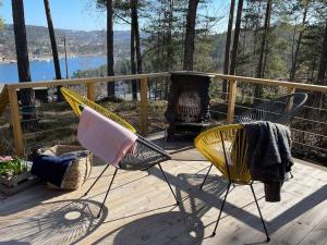 Summer cabin in Nesodden open-air bath large terrace في Brevik: سطح مع كرسيين ومدفأة