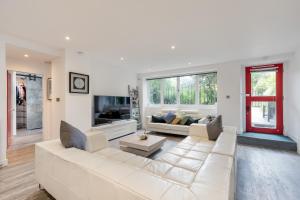 a living room with a white couch and a tv at Luxury Architect Designed Apt 13 Mins to Royal mile in Edinburgh
