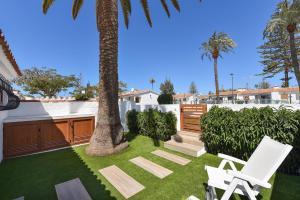 a yard with two chairs and a palm tree at Bungalow Santa Barbara EMC2 by VillaGranCanaria in Playa del Ingles
