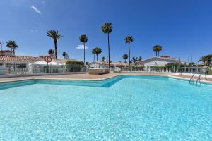 a large blue swimming pool with palm trees in the background at Bungalow Santa Barbara EMC2 by VillaGranCanaria in Playa del Ingles