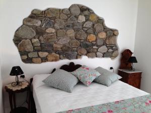 1 dormitorio con una pared de piedra sobre una cama en Crotto Regina, en Gravedona