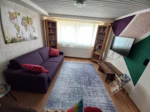 a living room with a purple couch and a television at FeWo Heidenheim Bluewall in Heidenheim an der Brenz