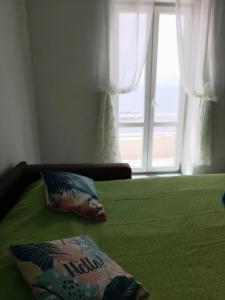 - un lit vert avec un oreiller et une fenêtre dans l'établissement La casa Verde, à Ischia