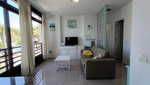 sala de estar con sofá y TV en alquilaencanarias El Medano beach 1, en El Médano