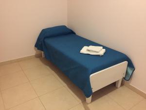 ein kleines Bett mit einer blauen Decke und einem Handtuch darauf in der Unterkunft El Oasis in Saladillo