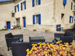 un patio con sillas y flores frente a un edificio en Relais de la poste, en Monclar-de-Quercy