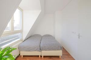 Bett in einem weißen Zimmer mit Fenster in der Unterkunft De Jutter in Den Helder