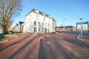 una calle de ladrillo con un edificio blanco en el lateral en De Jutter, en Den Helder