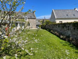 ein Haus mit einer Steinmauer und einem Hof mit weißen Blumen in der Unterkunft Gites La Ville Pain in Cancale