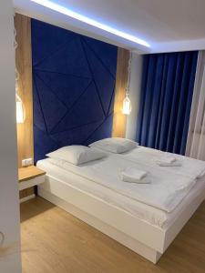ein Schlafzimmer mit einem großen weißen Bett und einer blauen Wand in der Unterkunft Rodos in Jaczów