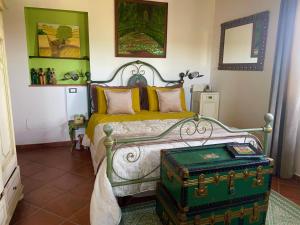 een slaapkamer met een bed met een groene koffer bij Bed and Breakfast Casale del Sole in Castellina Marittima