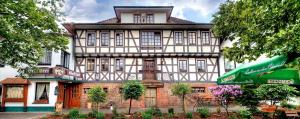 a large white and brown building with a green umbrella at Hotelgasthof Schmucker in Mossautal