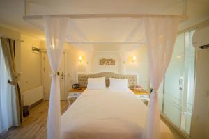 a bedroom with a white bed with white curtains at Biga Palas Hotel in Biga