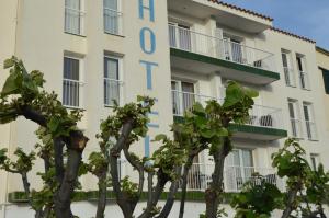 un bâtiment avec des arbres devant lui dans l'établissement Hotel Nou Estrelles, à Cadaqués