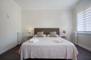 a white bedroom with a bed with two towels on it at Consell de Cent Apartment in Barcelona