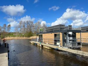 ein Holzhaus auf einer Anlegestelle an einem Fluss in der Unterkunft Hausboot Resort Nordseeküste in Wilhelmshaven