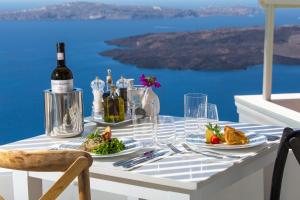 a table with a bottle of wine and plates of food at Iconic Santorini, a Boutique Cave Hotel by Sandglass in Imerovigli