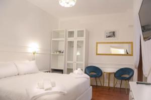 a bedroom with a white bed and two blue chairs at Mama House Roma in Rome